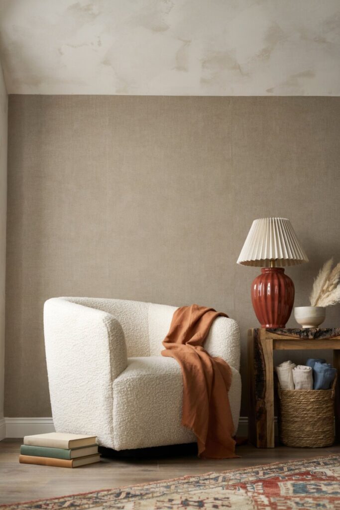 A boucle armchair next to a glossy ceramic lamp on a raw-edge wood side table